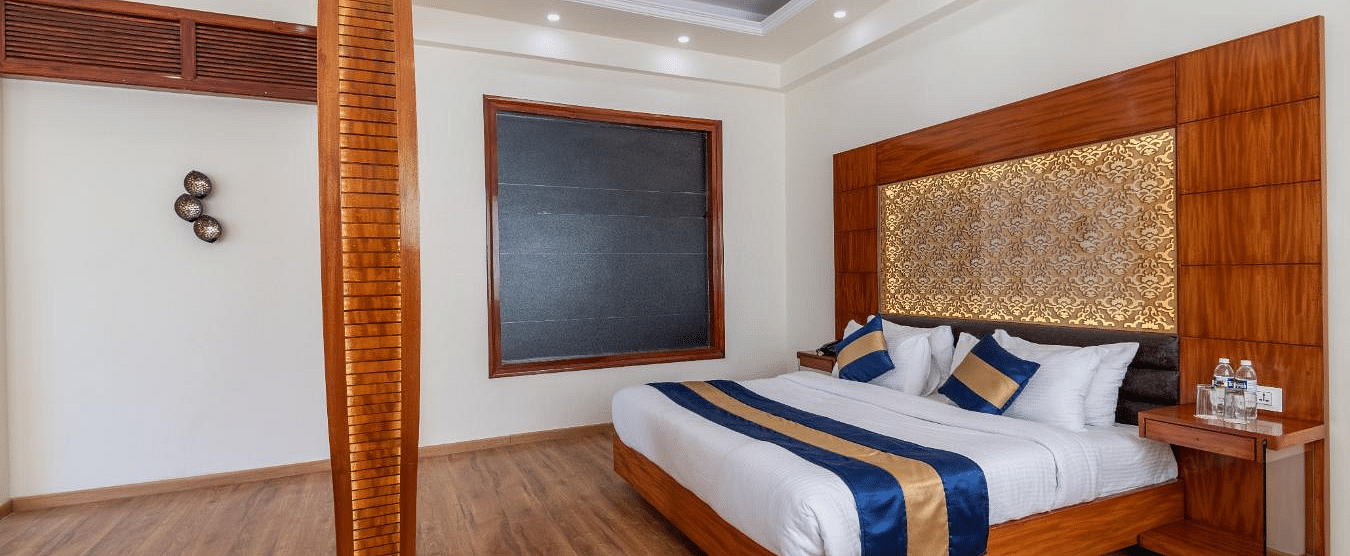 Image of the hotel bedroom with a king size bed and wooden furnishing  | DLS Serenity Resort and Spa